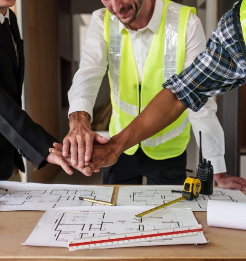 Architecture team stacking hands working together. Architectural plan, civil, engineer sketching a construction project concept